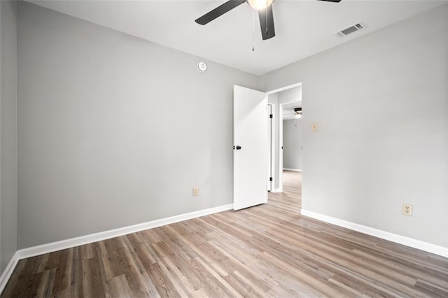 unfurnished room with wood finished floors, a ceiling fan, visible vents, and baseboards