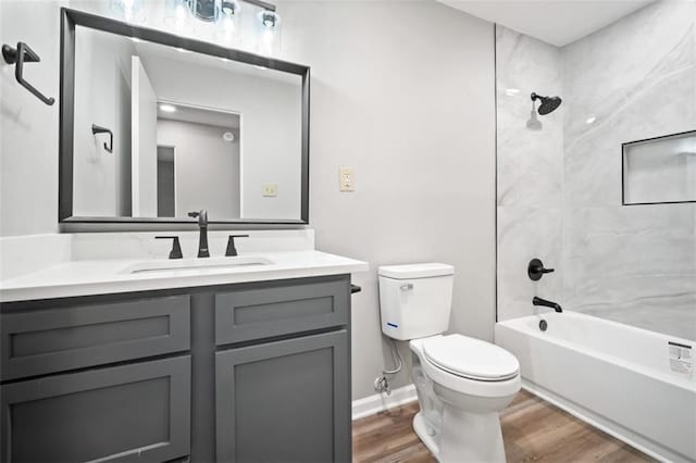 bathroom featuring toilet, wood finished floors, shower / bath combination, baseboards, and vanity