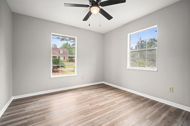 spare room with plenty of natural light, wood finished floors, baseboards, and ceiling fan