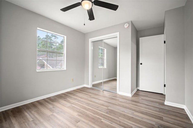 unfurnished bedroom featuring a closet, a ceiling fan, baseboards, and wood finished floors