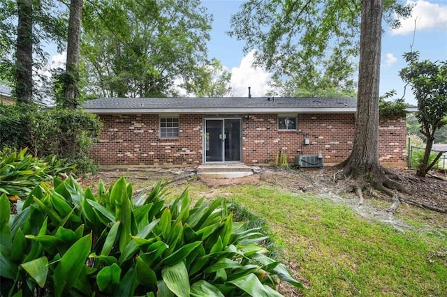 rear view of property featuring entry steps, central AC unit, and brick siding