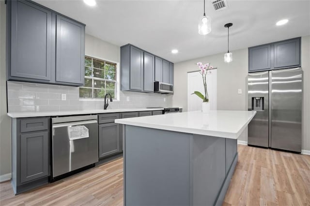kitchen with tasteful backsplash, light wood finished floors, appliances with stainless steel finishes, and gray cabinetry