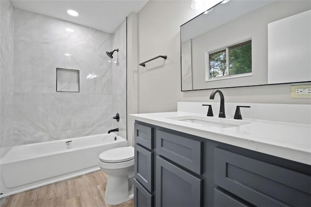 bathroom with toilet, recessed lighting, bathtub / shower combination, wood finished floors, and vanity