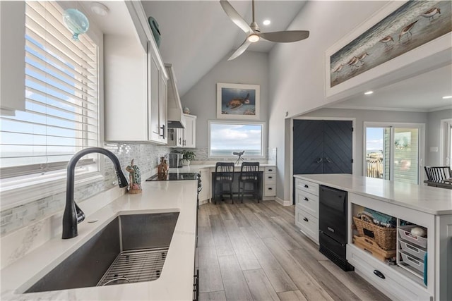 kitchen with sink, white cabinetry, decorative backsplash, light hardwood / wood-style flooring, and ceiling fan