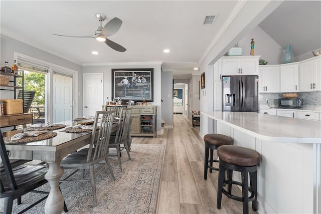 dining area featuring crown molding, lofted ceiling, ceiling fan, and light hardwood / wood-style flooring