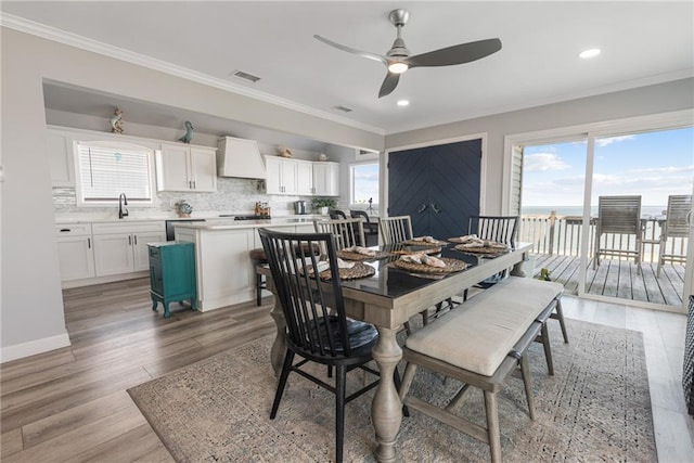 dining space with crown molding, light hardwood / wood-style floors, sink, and ceiling fan