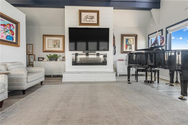 sitting room with vaulted ceiling with beams, a multi sided fireplace, and hardwood / wood-style floors