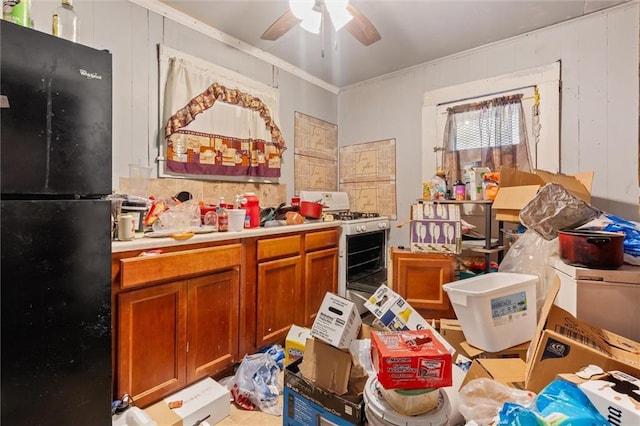 kitchen featuring black fridge, crown molding, gas range gas stove, and wood walls