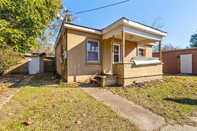 bungalow-style house featuring a storage unit and a front lawn