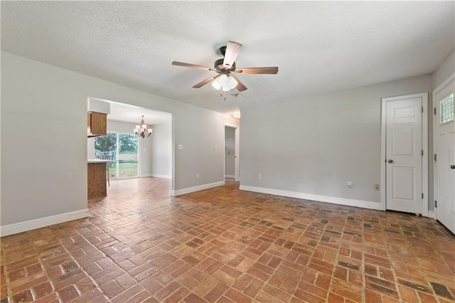 empty room with ceiling fan with notable chandelier and a textured ceiling