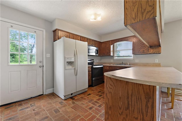 kitchen featuring a textured ceiling, range with electric cooktop, kitchen peninsula, and white refrigerator with ice dispenser