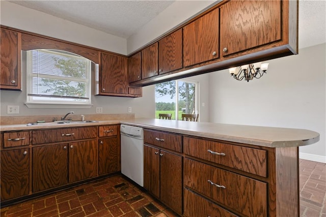 kitchen with a chandelier, kitchen peninsula, white dishwasher, sink, and a textured ceiling