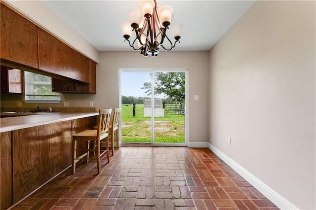 kitchen with decorative light fixtures, a notable chandelier, a wealth of natural light, and a breakfast bar