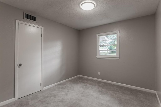 carpeted empty room featuring a textured ceiling