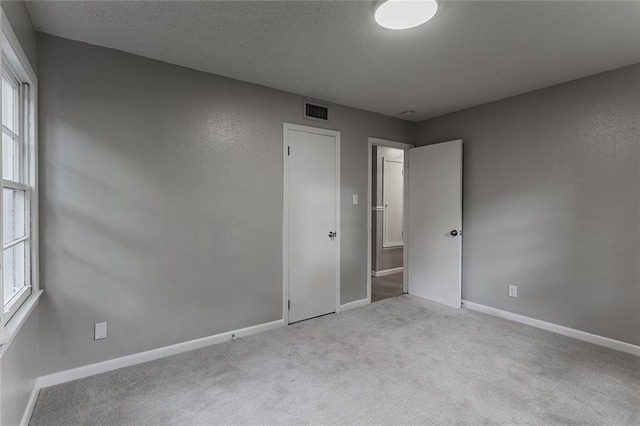 unfurnished room featuring light colored carpet and a textured ceiling