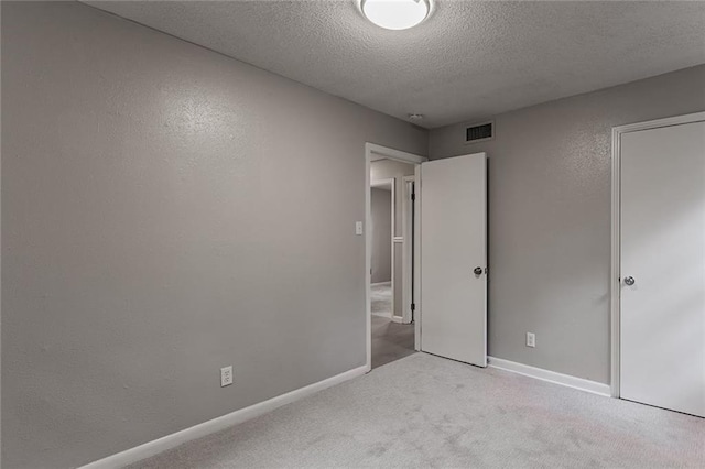 unfurnished bedroom with a textured ceiling and light colored carpet