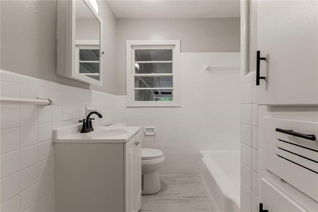 bathroom featuring vanity, toilet, tile walls, and a tub