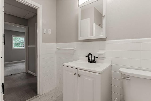 bathroom with hardwood / wood-style floors, vanity, toilet, and tile walls