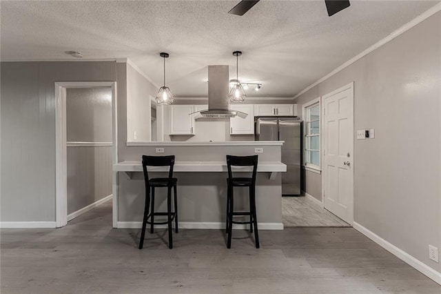 kitchen with light wood-type flooring, white cabinetry, island exhaust hood, and stainless steel refrigerator