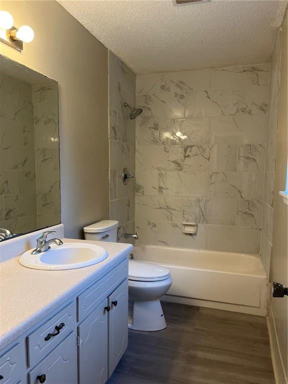 full bathroom with toilet, vanity, a textured ceiling, tiled shower / bath combo, and hardwood / wood-style flooring