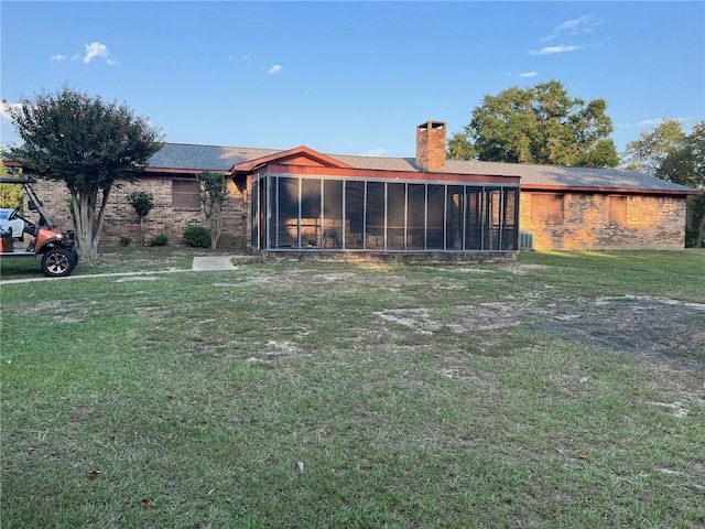 back of property featuring a lawn and a sunroom