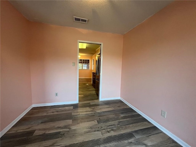 spare room with dark wood-type flooring and a textured ceiling