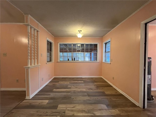 empty room with a textured ceiling, ornamental molding, and dark hardwood / wood-style floors