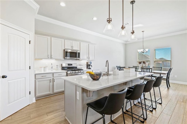 kitchen featuring a kitchen breakfast bar, pendant lighting, a kitchen island with sink, appliances with stainless steel finishes, and light wood-type flooring