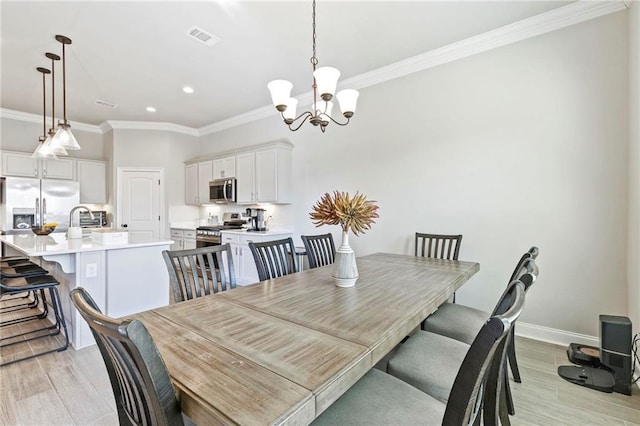 dining area featuring a notable chandelier, ornamental molding, sink, and light hardwood / wood-style flooring