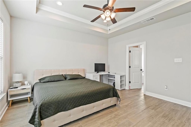 bedroom with light hardwood / wood-style flooring, ornamental molding, and a raised ceiling