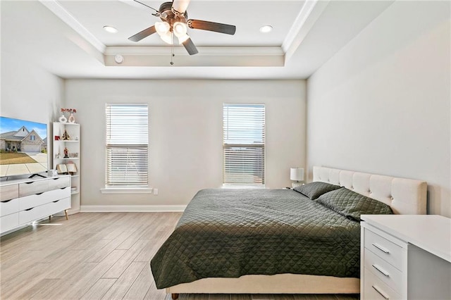 bedroom featuring a tray ceiling, multiple windows, ceiling fan, and light hardwood / wood-style flooring