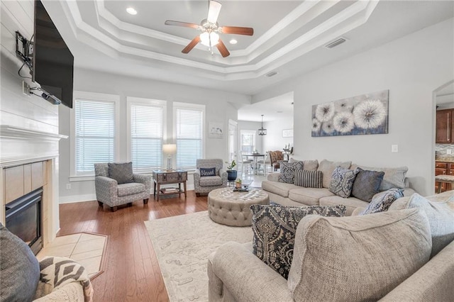 living room with hardwood / wood-style flooring, a healthy amount of sunlight, and a raised ceiling