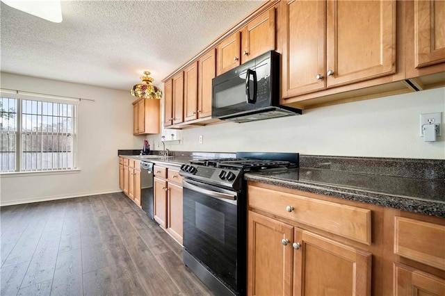 kitchen with dishwasher, dark stone countertops, dark hardwood / wood-style floors, stainless steel range, and a textured ceiling