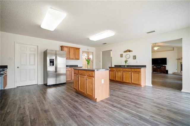 kitchen featuring a center island, a textured ceiling, stainless steel fridge, and dark hardwood / wood-style flooring