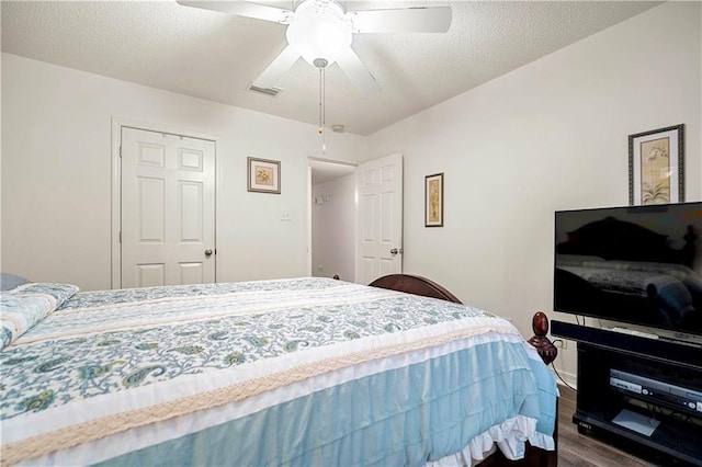 bedroom with ceiling fan, dark hardwood / wood-style floors, and a textured ceiling