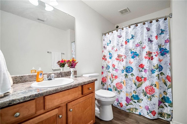 bathroom with vanity, wood-type flooring, a textured ceiling, and toilet