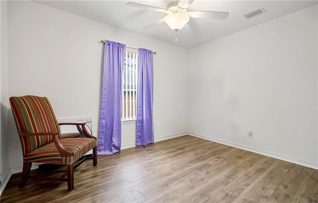 living area with wood-type flooring and ceiling fan