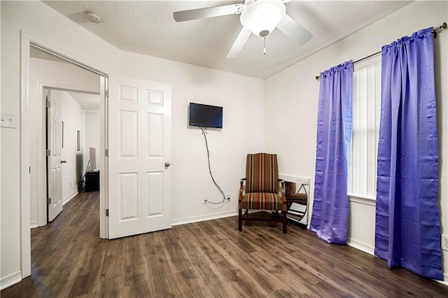 living area with ceiling fan, a textured ceiling, and dark hardwood / wood-style flooring