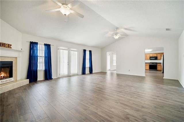 unfurnished living room featuring dark hardwood / wood-style flooring, a fireplace, lofted ceiling, and ceiling fan