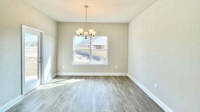 unfurnished dining area with a notable chandelier, dark hardwood / wood-style floors, and a healthy amount of sunlight