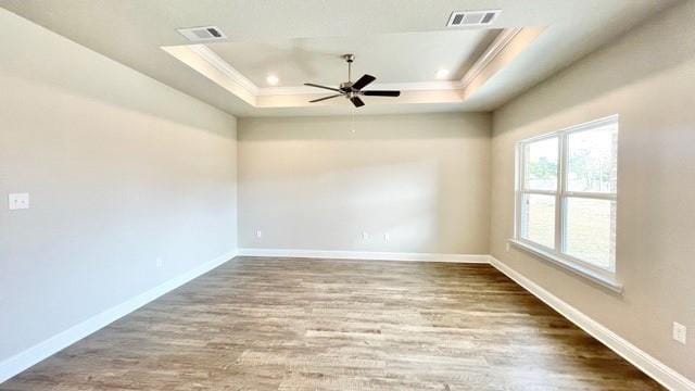 unfurnished room featuring crown molding, wood-type flooring, a raised ceiling, and ceiling fan