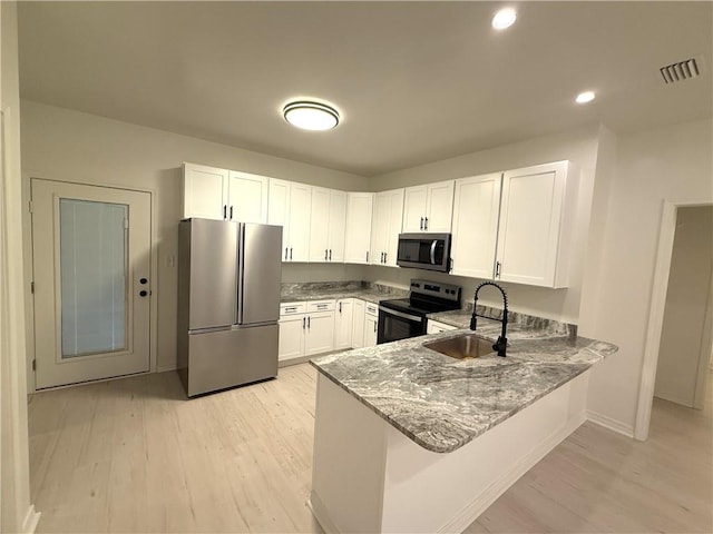755 Cadillac Ave, Dauphin Island, AL 36528 - kitchen with stainless steel appliances, light wood-style flooring, white cabinetry, light stone counters, and recessed lighting