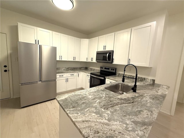 755 Cadillac Ave, Dauphin Island, AL 36528 - kitchen featuring stainless steel appliances, a peninsula, light stone counters, and light wood finished floors