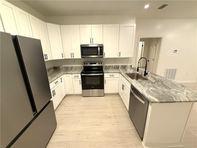 755 Cadillac Ave, Dauphin Island, AL 36528 - kitchen featuring appliances with stainless steel finishes, light wood finished floors, a peninsula, recessed lighting, and stone counters