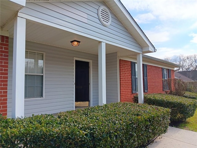 view of exterior entry with covered porch and brick siding