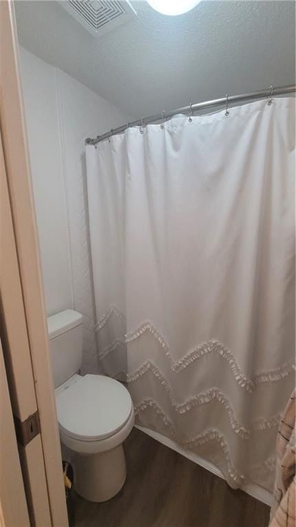 bathroom featuring a textured ceiling, toilet, and hardwood / wood-style floors