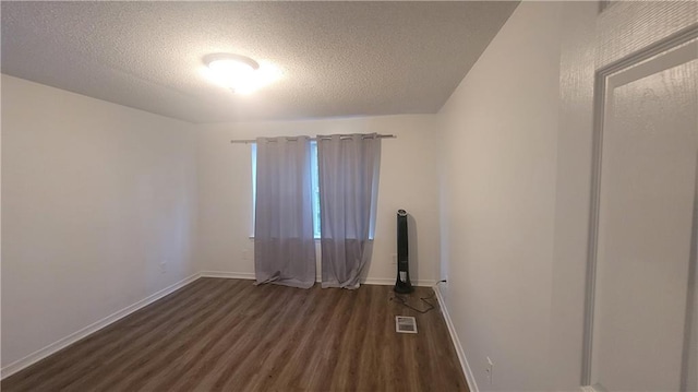 spare room featuring a textured ceiling and dark wood-type flooring