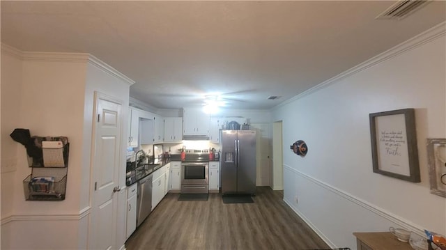 kitchen featuring white cabinets, crown molding, dark wood-type flooring, appliances with stainless steel finishes, and sink