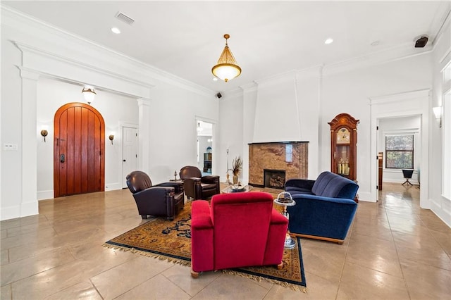 tiled living room with decorative columns, crown molding, and a fireplace