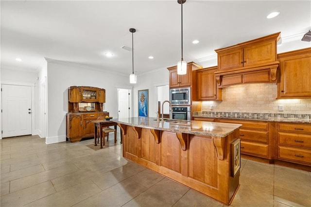 kitchen with a kitchen bar, sink, pendant lighting, stainless steel appliances, and a kitchen island with sink